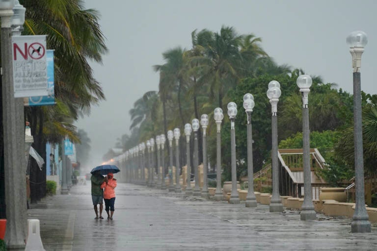 A pair of beach goers walk on the Hollywood Beach Broadwalk as conditions deteriorate with the approach of Hurricane Nicole, Wednesday, Nov. 9, 2022, in Hollywood Beach in Hollywood, Fla. (AP Photo/Wilfredo Lee)