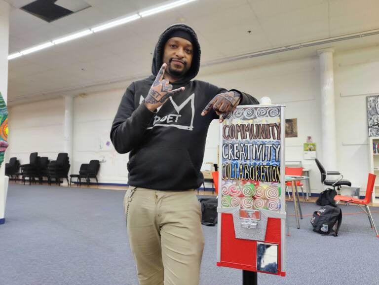 Lindo Jones, aka LindoYes!, with one of his gumball machines dispensing poetry and information for mental health resources, at the new headquarters of the Painted Bride in West Philadelphia. (Peter Crimmins/WHYY)