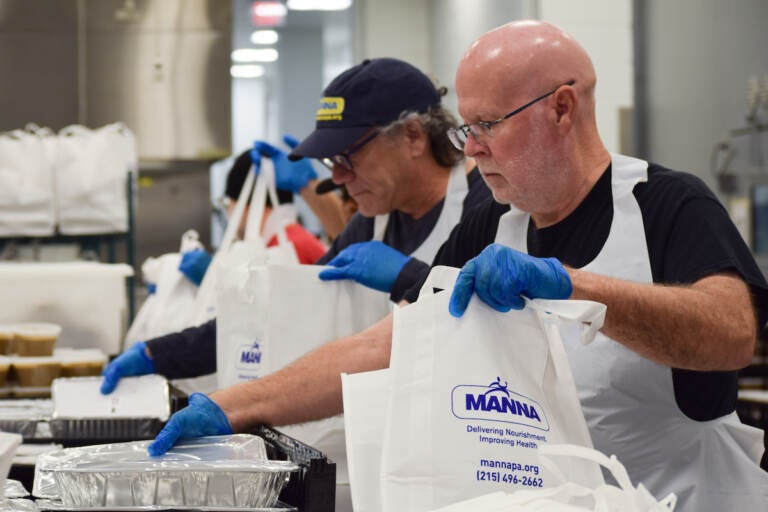 Volunteers work to put together Thanksgiving meal bags at the Metropolitan Area Neighborhood Nutrition Alliance (MANNA) in Philadelphia, Thurs., Nov. 24, 2022. (Nicole Leonard/WHYY)