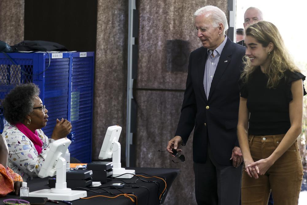 President Biden and granddaughter Natalie Biden stand and speak with a poll worker seated at a table.