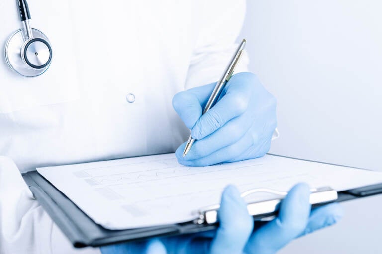 A medical person holds a clipboard in their hands.