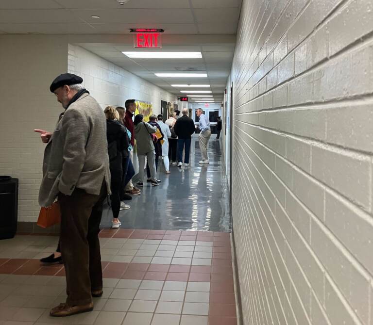 People wait in line in a hallway.