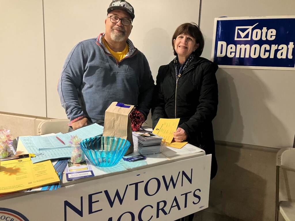 Two people stand behind a table with a sign that reads Newtown Democrats.