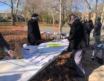 People gather around a table in a park.