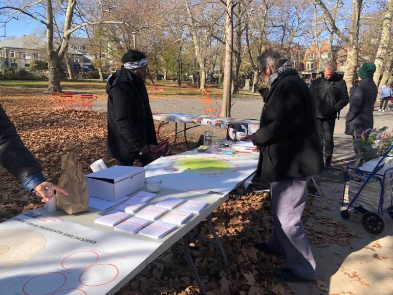 People gather around a table in a park.