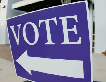 Voters walk past the sign pointing them to the polling location for in person voting in the general election, Tuesday, Nov. 8, 2022, in Cranberry Township, Pa. (