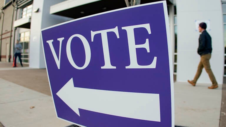 Voters walk past the sign pointing them to the polling location for in person voting in the general election, Tuesday, Nov. 8, 2022, in Cranberry Township, Pa. (