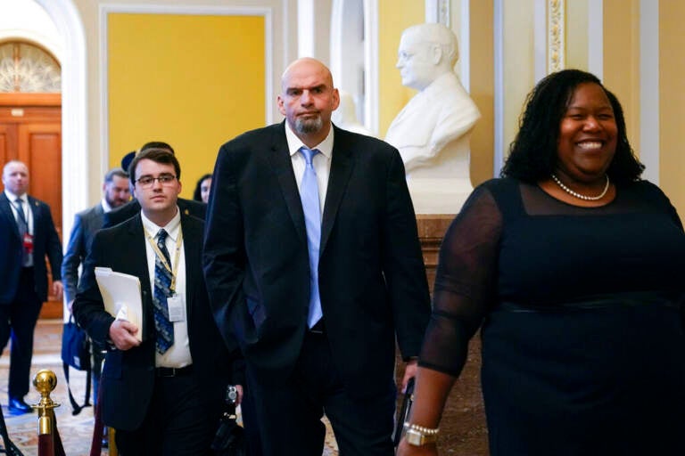 Fetterman walks along with other people down a hallway.