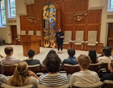 A rabbi addresses a group of people in a synagogue.