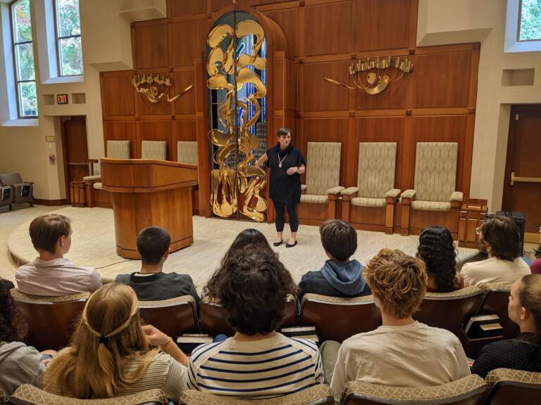 A rabbi addresses a group of people in a synagogue.
