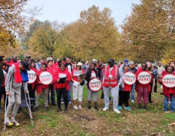 A group of people wearing red T-shirts pose with signs that read, 