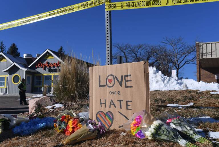 Bouquets of flowers and a sign reading ''Love Over Hate'' are left near Club Q