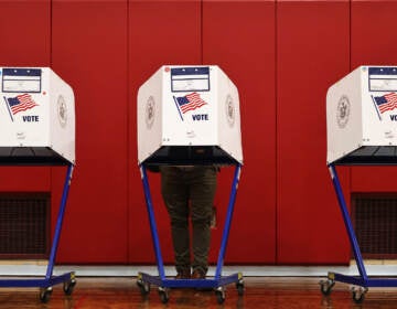 A person's legs are visible as they stand behind a voting booth.