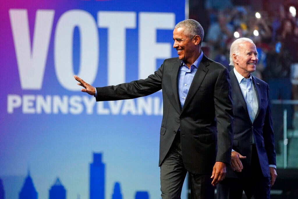 Obama waves as Joe Biden looks upward and smiles. Behind them is a sign that reads Vote Pennsylvania.