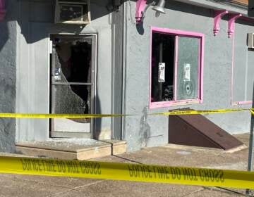 Police tape is pictured outside a salon, with windows broken from a shooting.