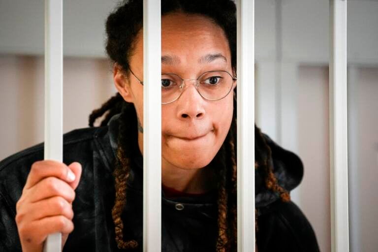 Brittney Griner stares through the bars of a cell.