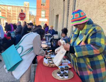 A vendor smiles as she prepares a purchase for a customer at her table.