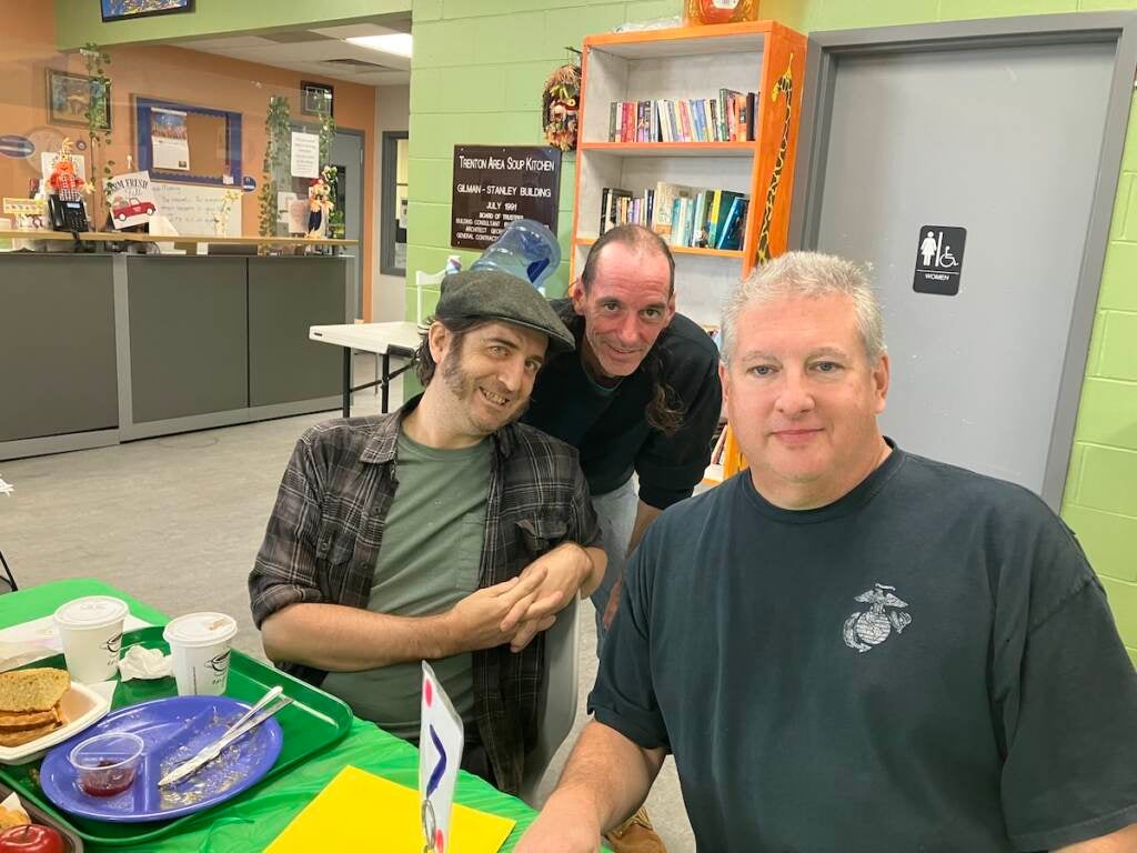 Three people pose for a photo seated at a table.