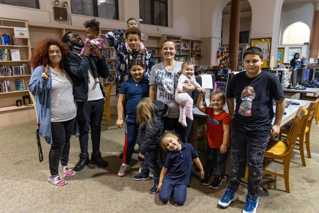 A group of people and kids stands in a library.