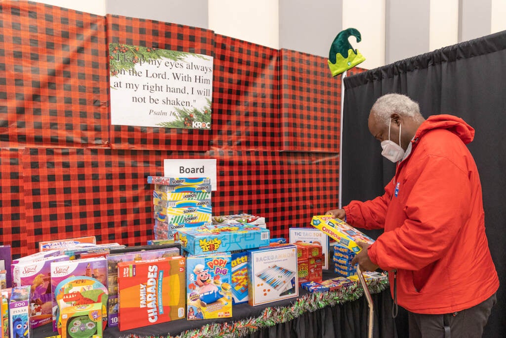 A man looks at a toy he selected from a table full of toys.