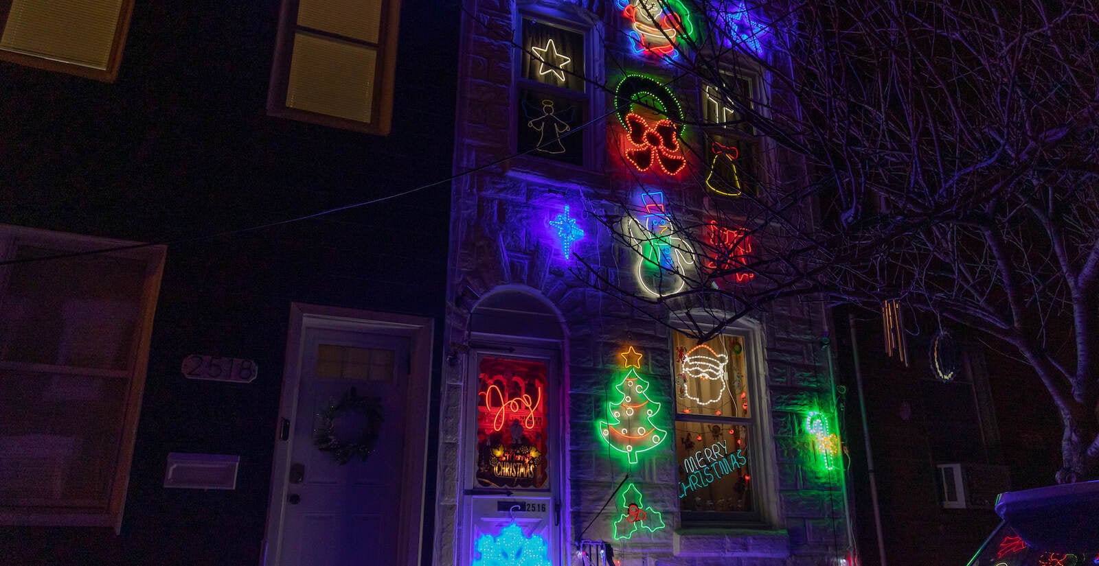 Three stories of neon decorations adorn the outside of a Fishtown rowhouse.