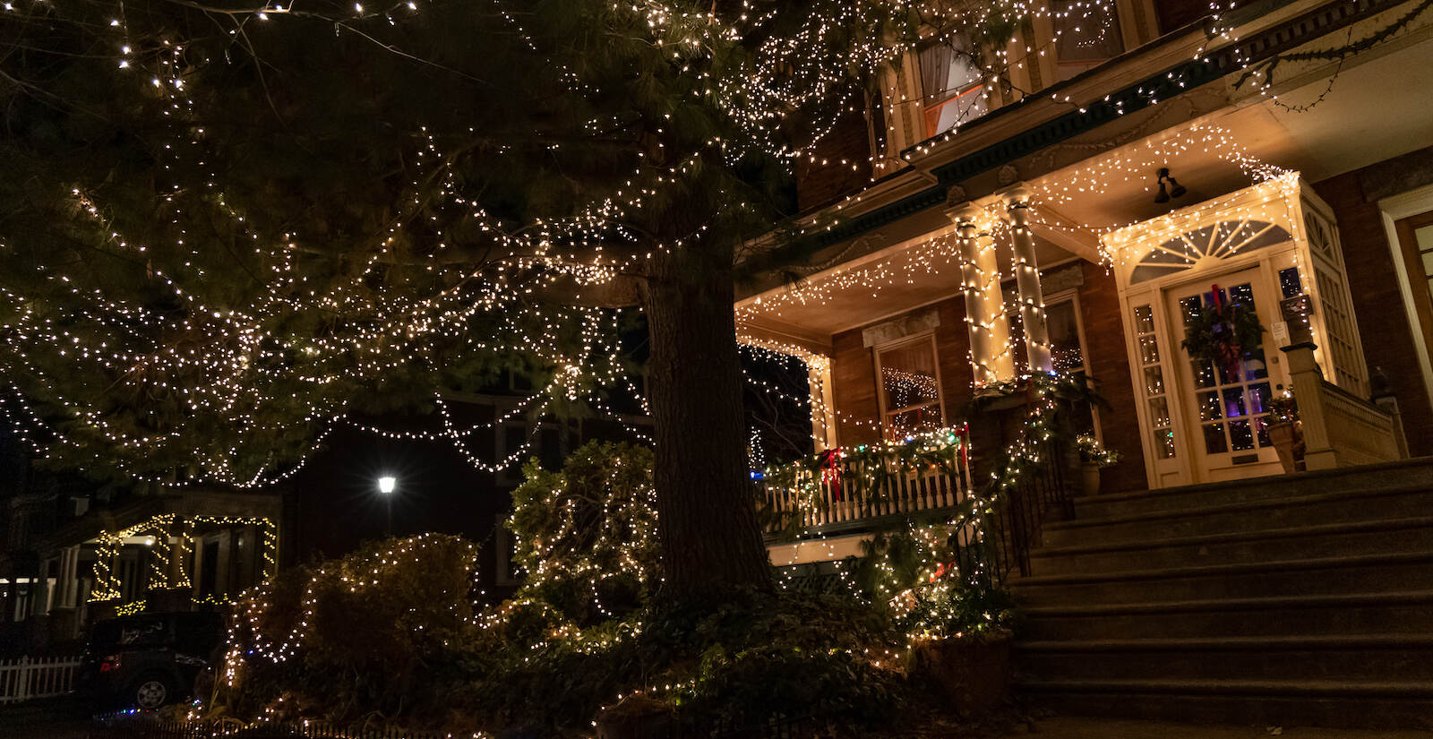 Warm white lights drape the entirety of a West Philadelphia corner house.