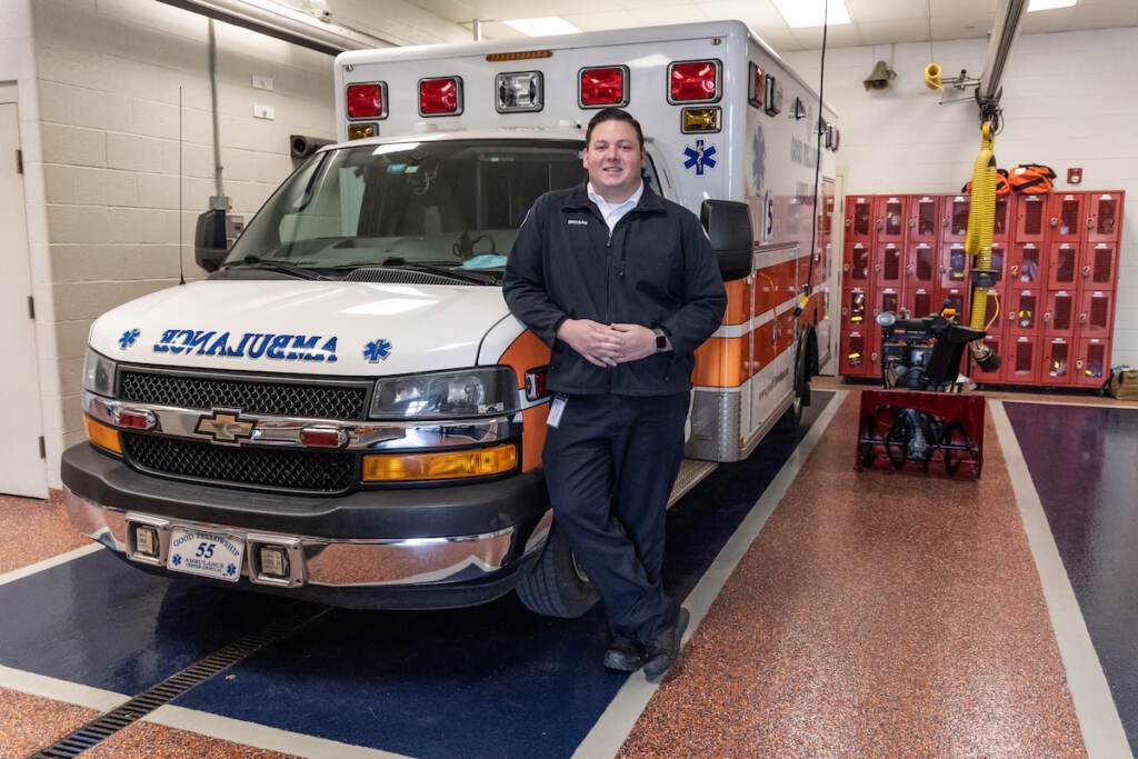 A man stands in front of an ambulance.