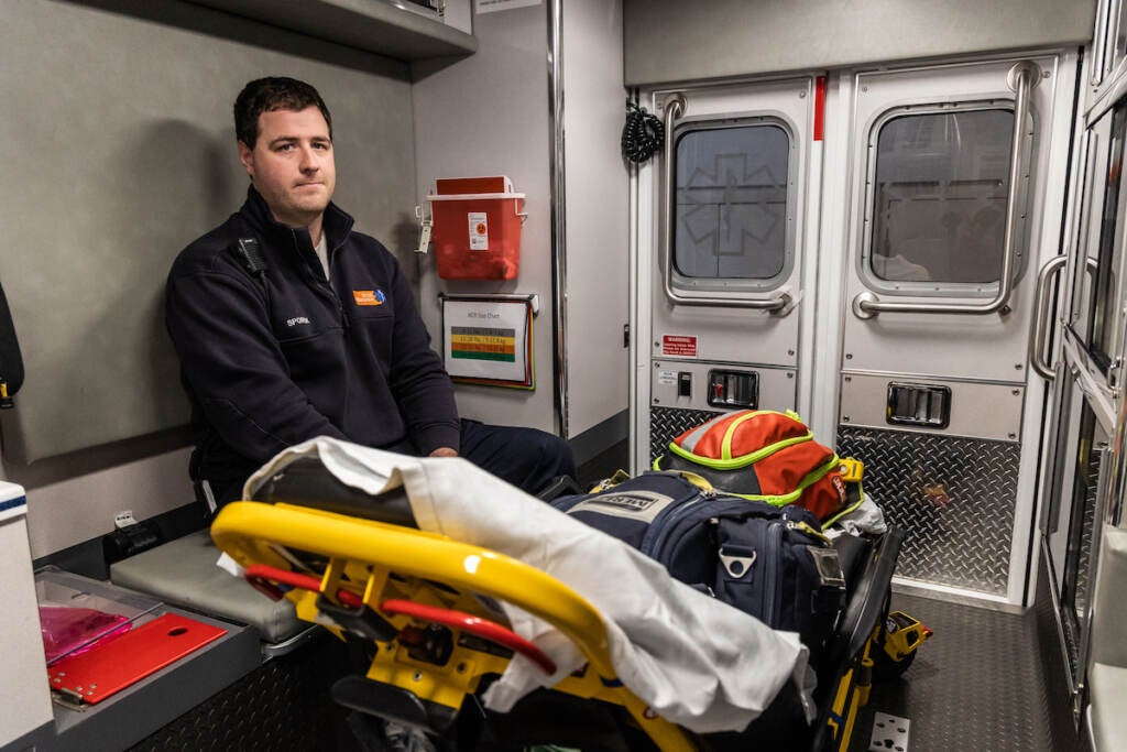 An EMT sits in the back of an ambulance.