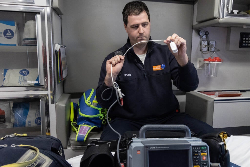 A man holds up a wire inside of an ambulance.