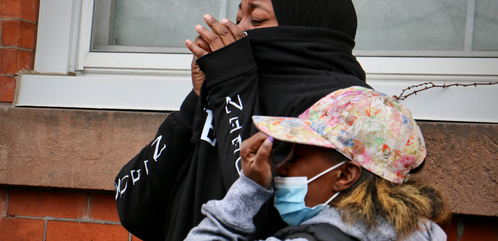 Women weep near the scene of a rowhouse fire