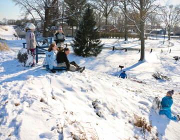 Children sled down the levee that separates Williamson Park from the Delaware River in Morrisville