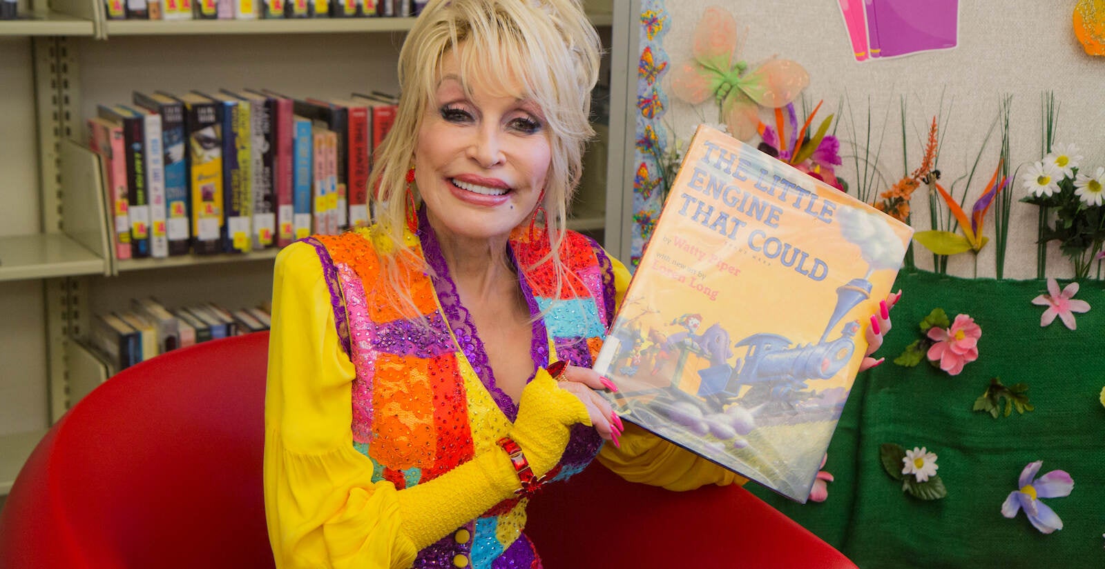 Dolly Parton holds up a children's book