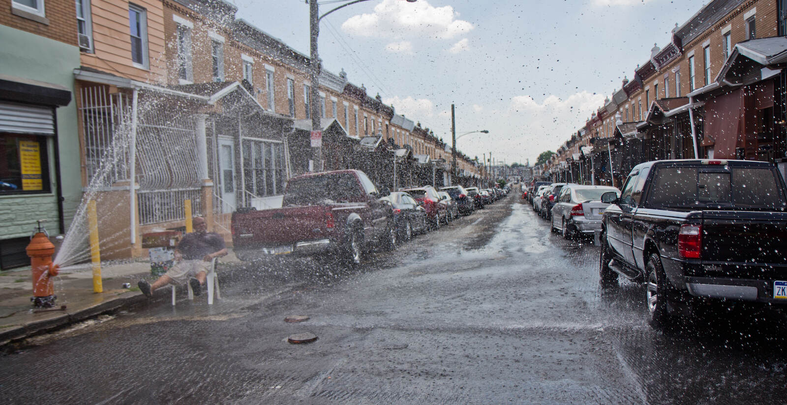 Philadelphia resident Daniel Tirado parks himself under an open fire hydrant during an intense heat wave