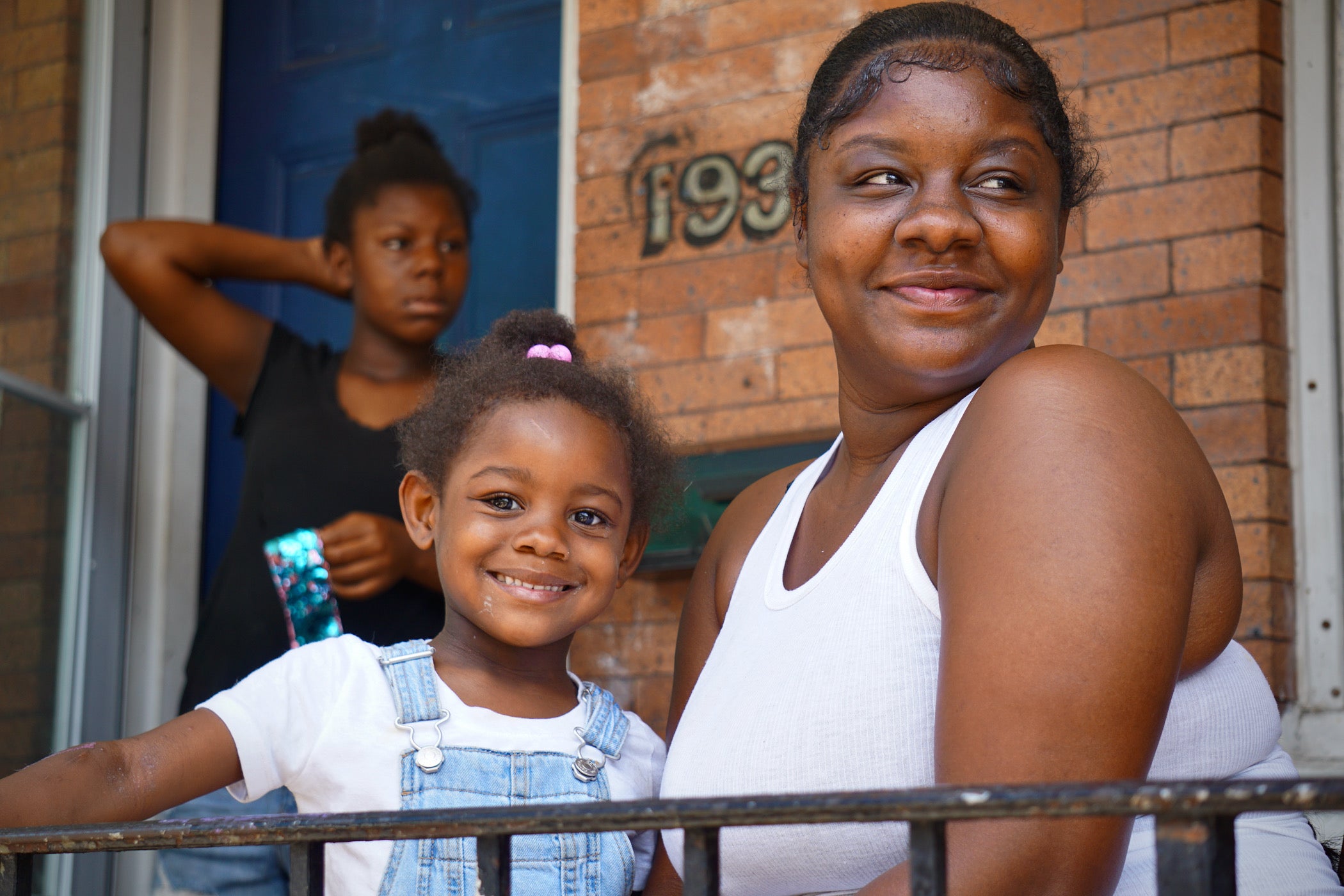 Kiara Askins and her daughter watch the Playstreet captains at work on their block in Kensington