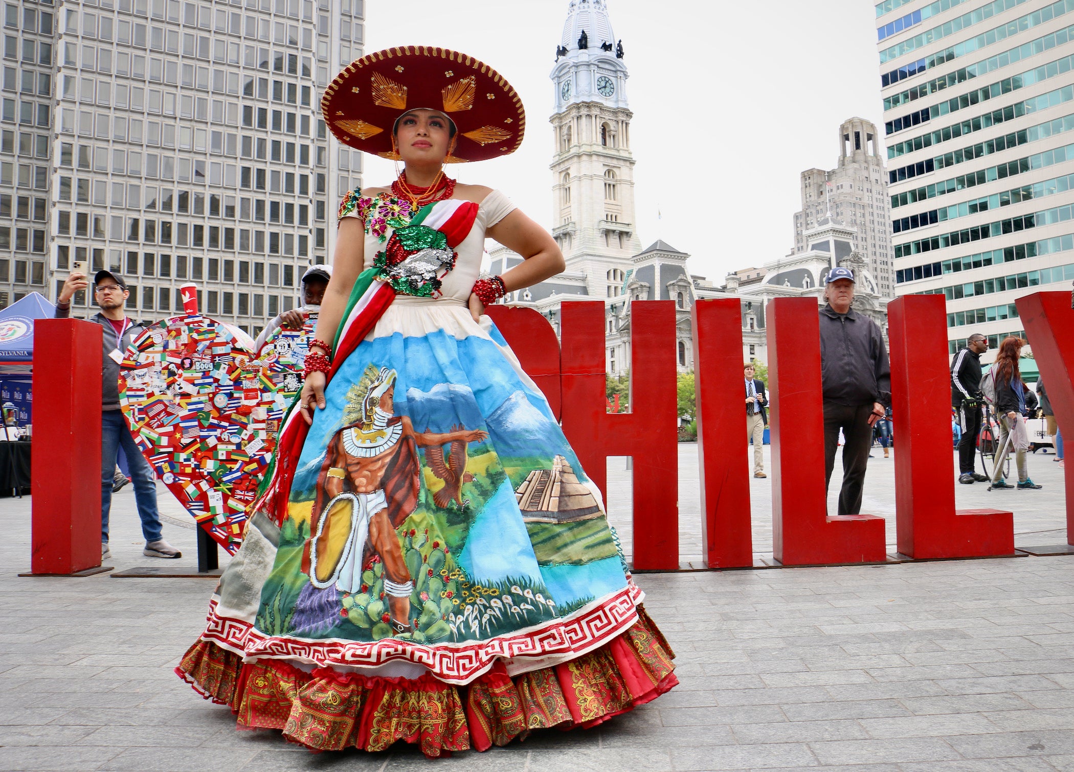 Cindy Diaz, in a painted dress depicting scenes from Mexican history, watches the stage show at the Latin America Thrives in Philadelphia event