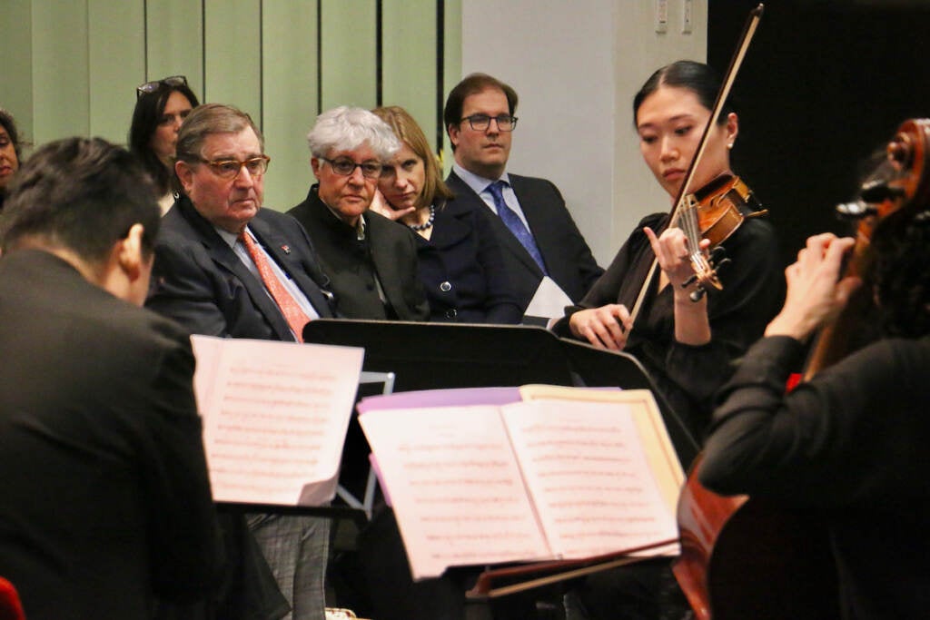 A group of people watch as a quartet plays.