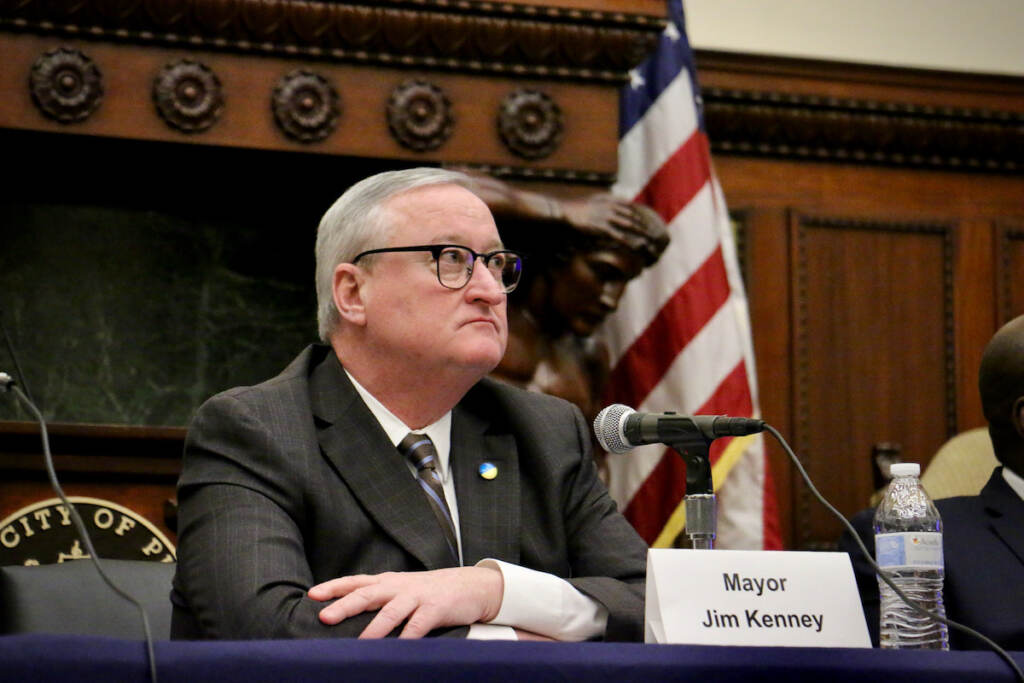 Mayor Kenney sits at a table in front of a microphone.