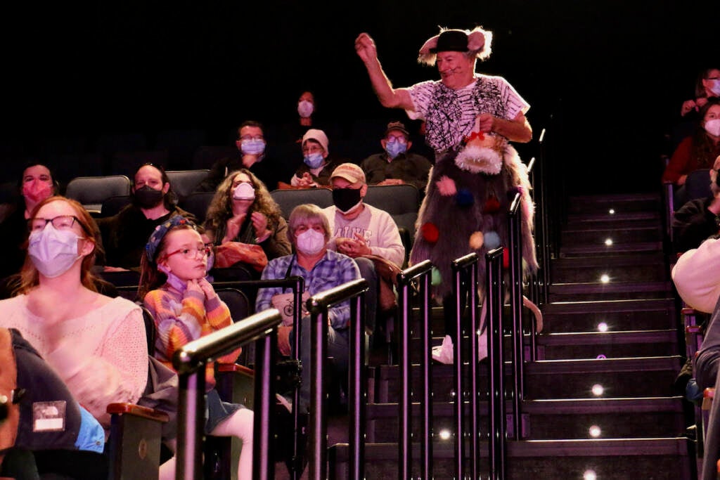 A performer walks down the aisle of a theater.