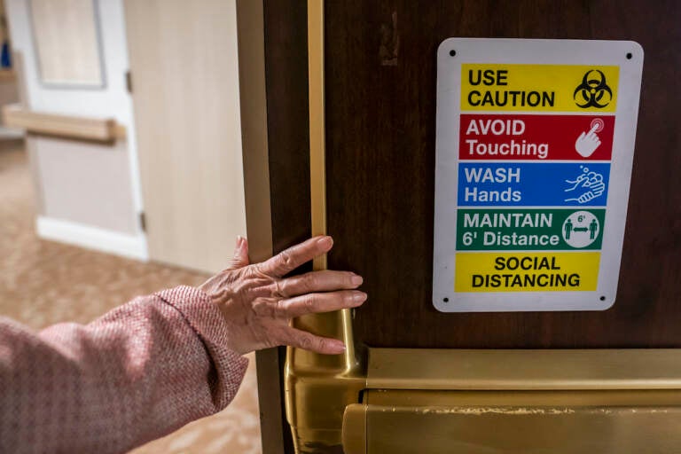 Tina Sandri, CEO of Forest Hills of DC senior living facility, passes a COVID-19 informational sign while walking to her office on Thursday, Dec. 8, 2022, in Washington. (AP Photo/Nathan Howard)