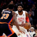 Philadelphia 76ers center Joel Embiid (21) looks to pass around New York Knicks center Mitchell Robinson during the first half of an NBA basketball game, Sunday, Dec. 25, 2022, in New York. (AP Photo/Adam Hunger)