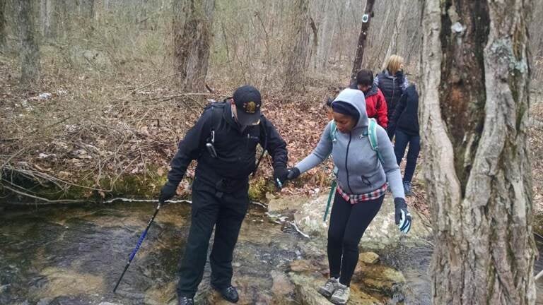 Hikers cross a stream in the forest.