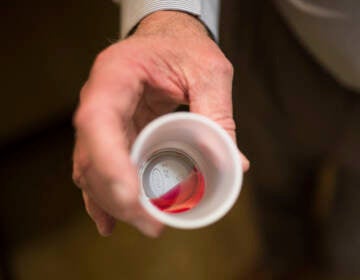 A person holds a cup with medicine in it.