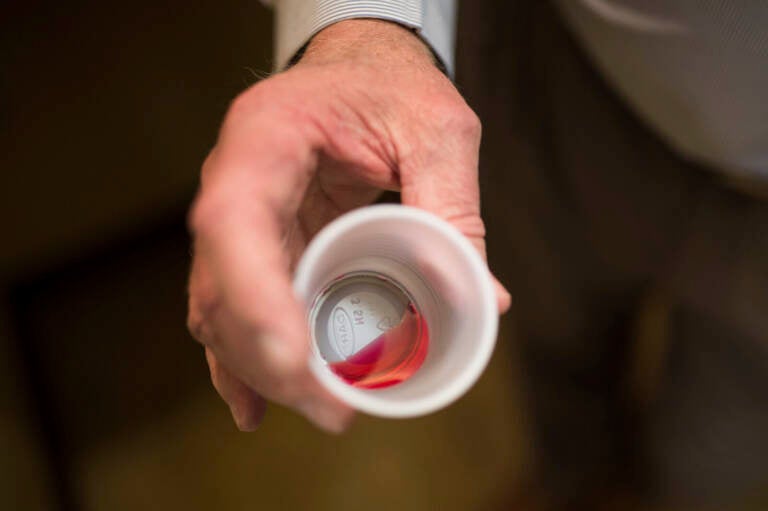 A person holds a cup with medicine in it.