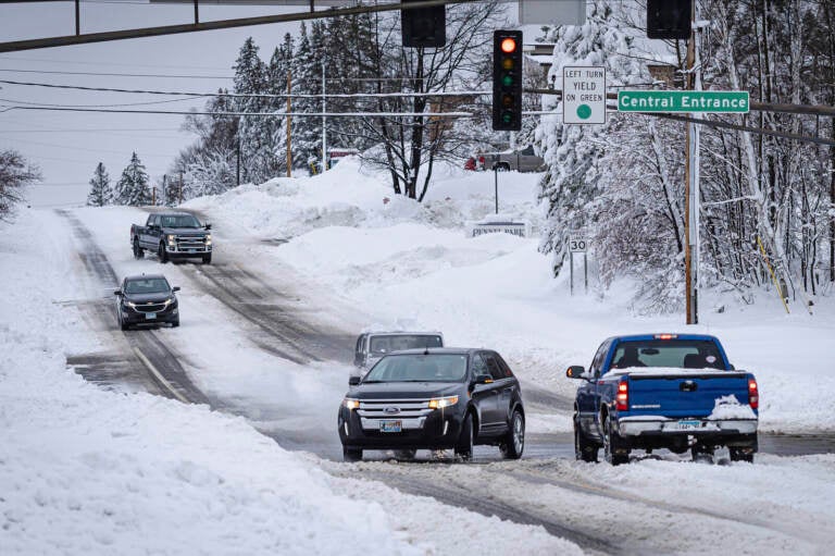 Cars are driving on a snow-packed road.