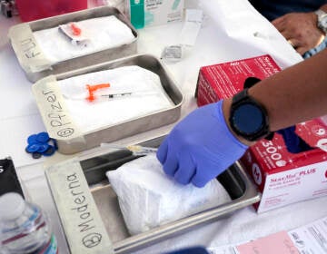 Modern and Pfizer COVID vaccines and flu vaccines sit in bins at a clinic