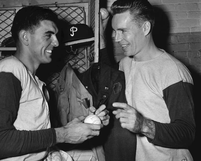 FILE - Philadelphia Phillies' Curt Simmons, left, autographs a ball for teammate John 'Jocko' Thompson before Game 1 of the World Series against the New York Yankees at Shibe Park in Philadelphia, Oct. 4, 1950. Simmons, the last surviving member of the 1950 Philadelphia Phillies 'Whiz Kids' team, died Tuesday, Dec. 13, 2022 in Ambler, Pa. He was 93. (AP Photo/File)