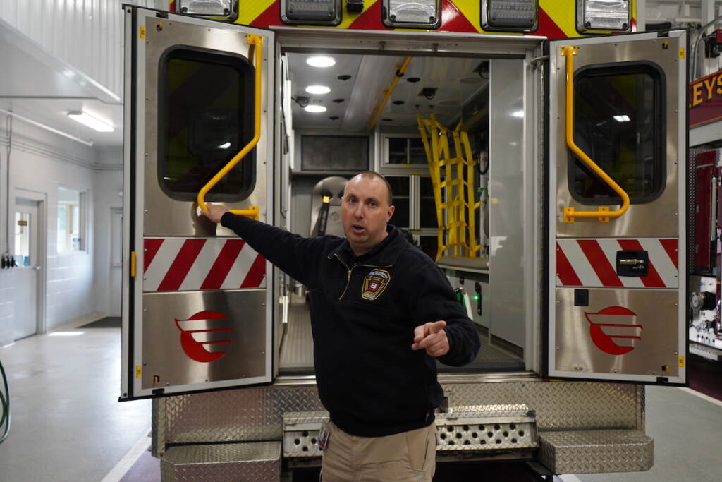 A man stands at the back of an ambulance.