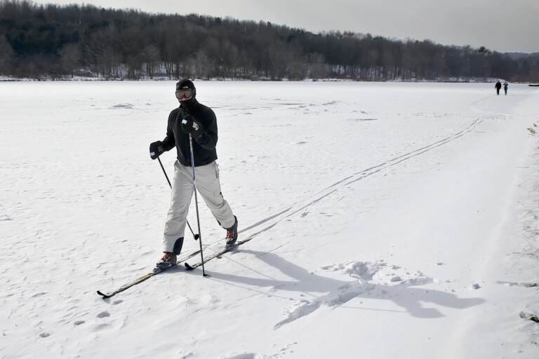 A man skis in an open, snow-covered field.