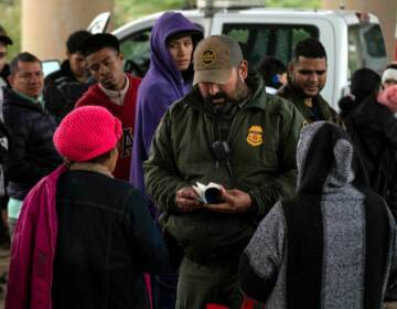  Border Patrol agent checks an asylum seeker's passport after she turned herself in, in Eagle Pass, Texas, on Dec. 19. (Veronica G. Cardenas/AFP via Getty Images)