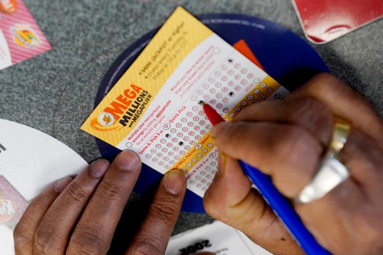A customer fills out a Mega Millions lottery ticket